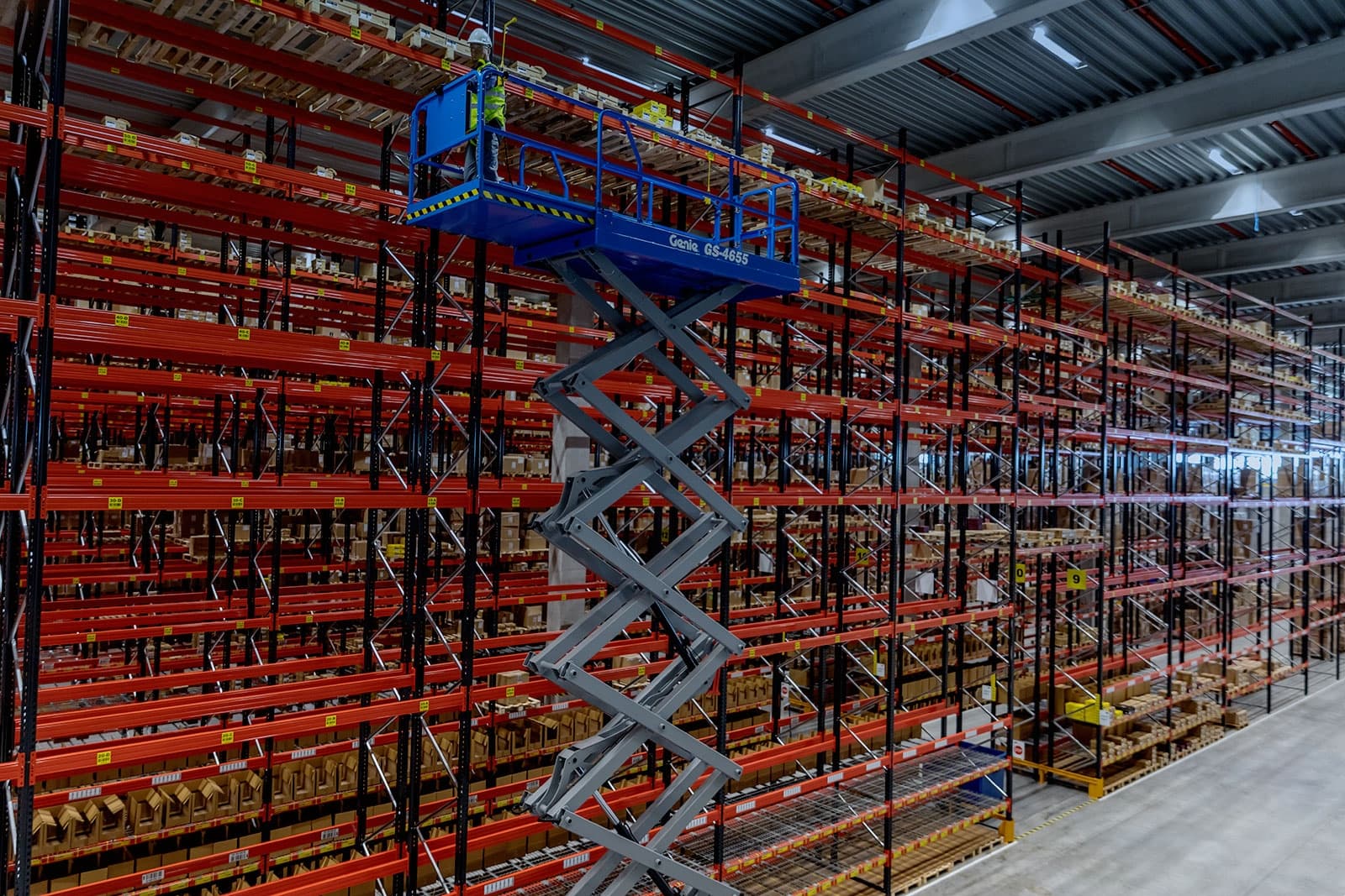 Scissor Lift elétrica autopropelida trabalhando em armazém interno.